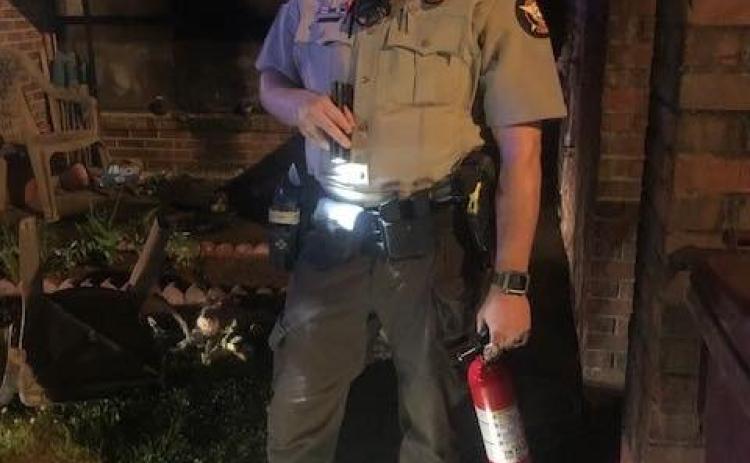 Submitted photo. Rabun County Sheriff’s Office Cpl. Cody Dills stands at the scene after he assisted with halting a May 1 fire.