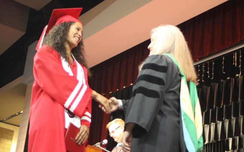 Megan Broome/The Clayton Tribune. Graduate Rissa McDonald shakes hands with Superintendent April Childers after receiving her diploma at last Friday’s ceremony. 