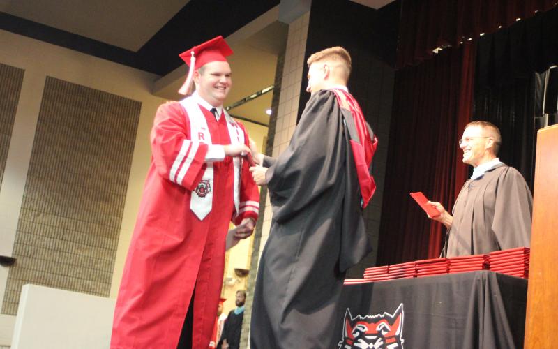 Megan Broome/The Clayton Tribune. Graduate Simon Bass is handed his high school diploma from RCHS Principal Justin Spillers at last Friday’s ceremony. 