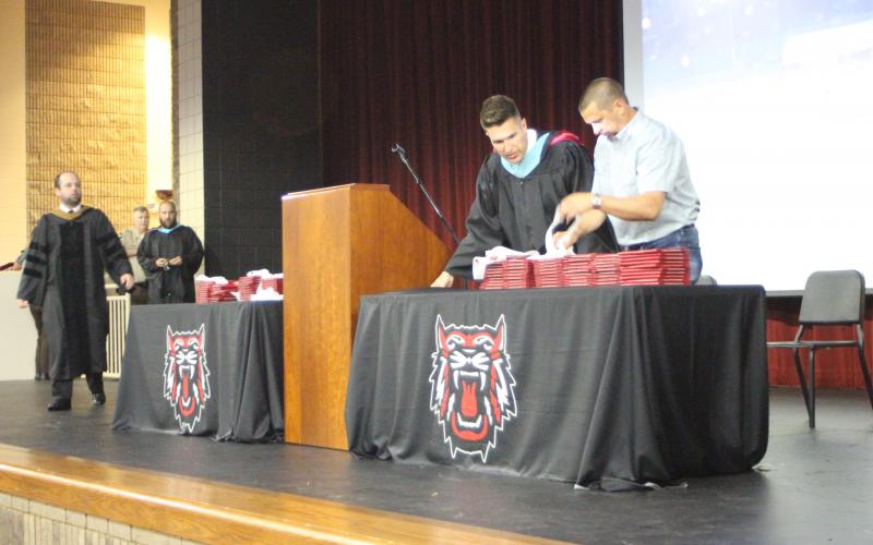 Megan Broome/The Clayton Tribune. School officials prepare the stage in the Rabun County Fine Arts building auditorium to hold graduation for the Class of 2021 after the ceremony moved inside due to weather conditions. Band Director Matt Leff, left, RCHS Principal Justin Spillers and Assistant Superintendent Jonathan Gibson help set up the stage. 
