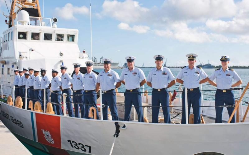 Photo courtesy of Sarah Ernst. Sarah Ernst (far right) stands aboard USCGC Assateague as the ship’s commander during her career with the U.S. Coast Guard.