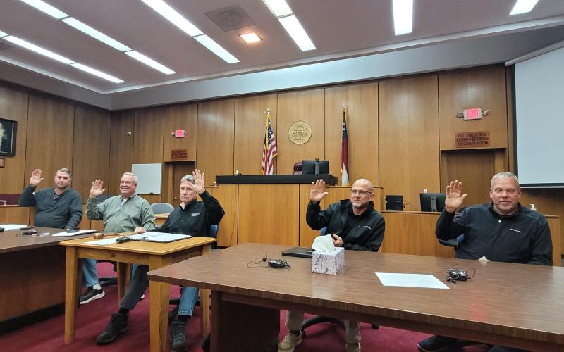 Megan Broome/The Clayton Tribune. Rabun County Commissioners Will Nichols, Kent Woerner, Chairman Greg James, Scott Crane and Tom Garrison raise their hands as they unanimously approve the first reading to amend the zoning ordinance for short-term rentals at Tuesday’s commission meeting.