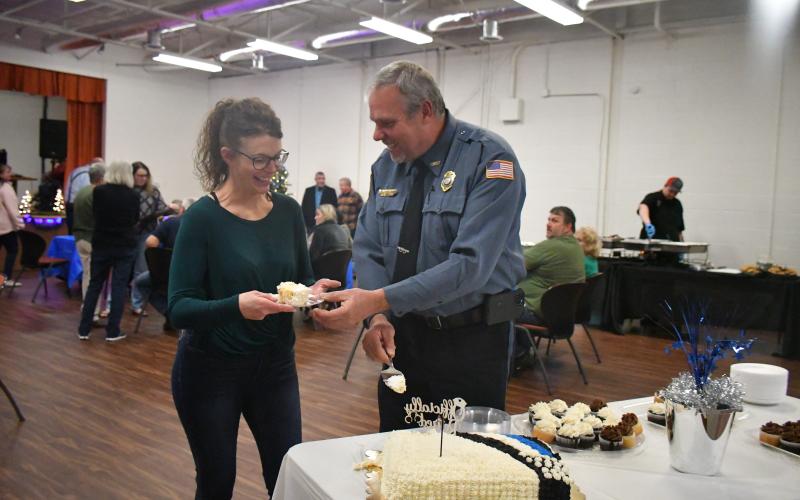 Megan Broome/The Clayton Tribune. Mountain City Police Chief Tom Garrison, with his wife Angie Garrison by his side, cuts the cake at his retirement reception from the City of Mountain City on Dec. 30, 2022. Garrison retires after serving as a law enforcement officer for 28 years and Mountain City Police Chief for 18 years.