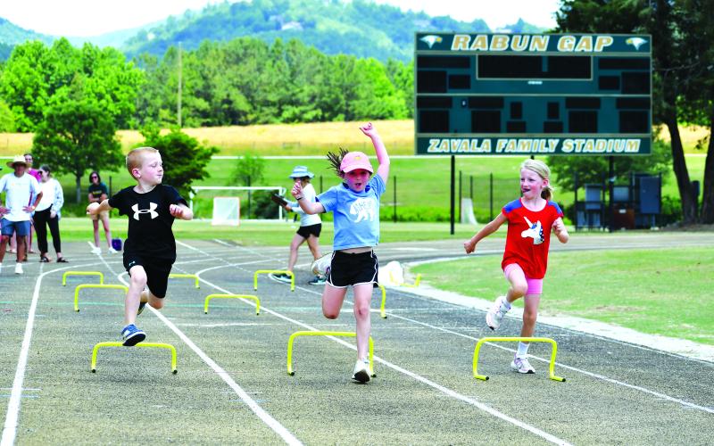 Luke Morey/The Clayton Tribune. Three Rabun Gap compete in a hurdles event on June 16.