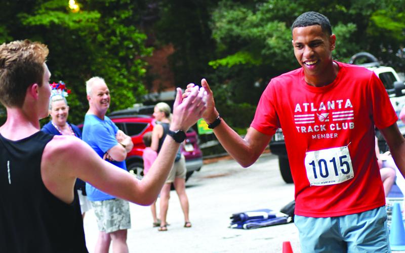 Enoch Autry/The Clayton Tribune. Alex Thomas (left) congratulates his Atlanta Track Club teammate Tristan Antg on a great 5K run at the Rabun Ramble. Thomas took first; Antg took third; and track club teammate Jack Voss took second.