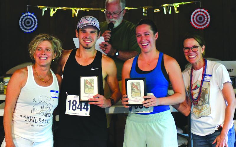 Enoch Autry/The Clayton Tribune. Rabun Ramble founder Sandy Strong and event organizer Mary Shannon Scott stand with the top male and female 10K finishers Joseph Ham and Parker Rhodes.
