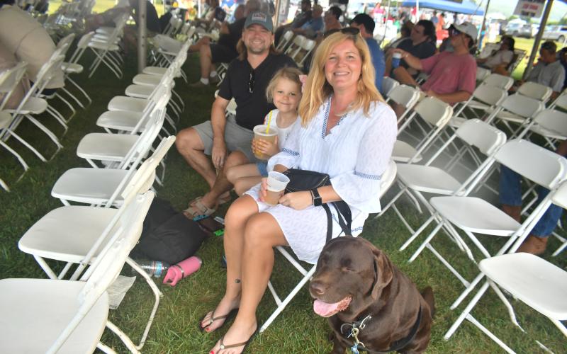 Megan Broome/The Clayton Tribune. Michael, Lilly, 6, and Sara Caveney enjoy bluegrass music with dog Rohan during the 26th Dillard Bluegrass Festival.
