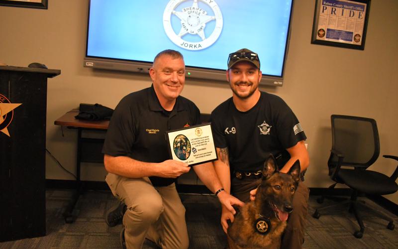 Megan Horn/The Clayton Tribune. Rabun County Sheriff Chad Nichols presents K9 Jorka and partner Cpl. Clinton Scott with a plaque thanking the K9 for six years of honorable service at the Rabun County Sheriff’s Office. K9 Deputy Jorka officially retired September 8. 