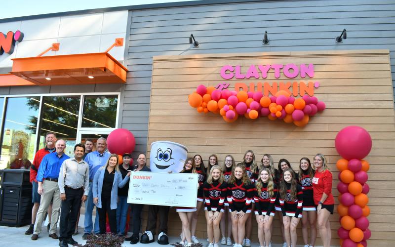 Megan Horn/The Clayton Tribune. Rabun County Athletics is presented with a $500 donation check from Dunkin' Donuts during the grand opening Sept. 30. Below: Megan Horn/The Clayton Tribune. Lucy Woerner poses with Cuppy during the Sept. 30 Dunkin' Donuts grand opening. 