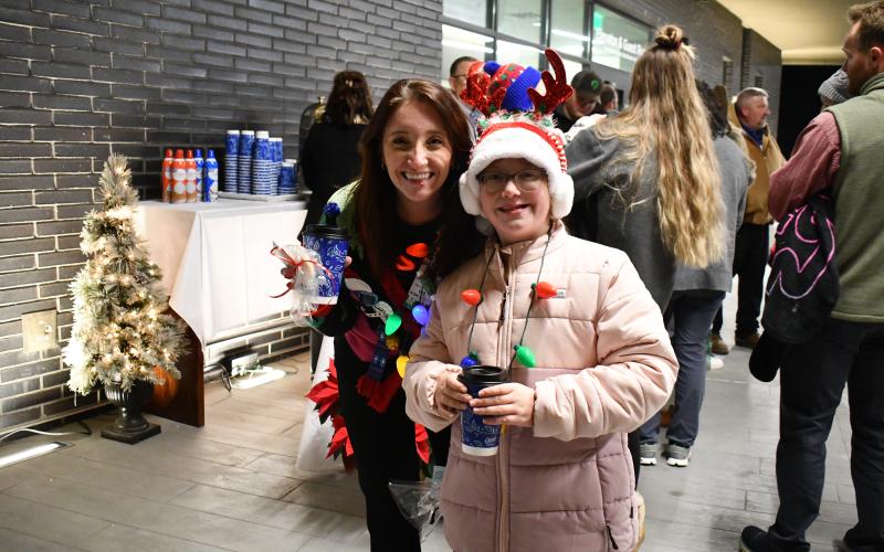Megan Horn/The Clayton Tribune. Lacey and Allison Stockton dress up in festival holiday gear as they sip hot chocolate and enjoy the event at Mountain Lakes Medical Center Dec. 14. 