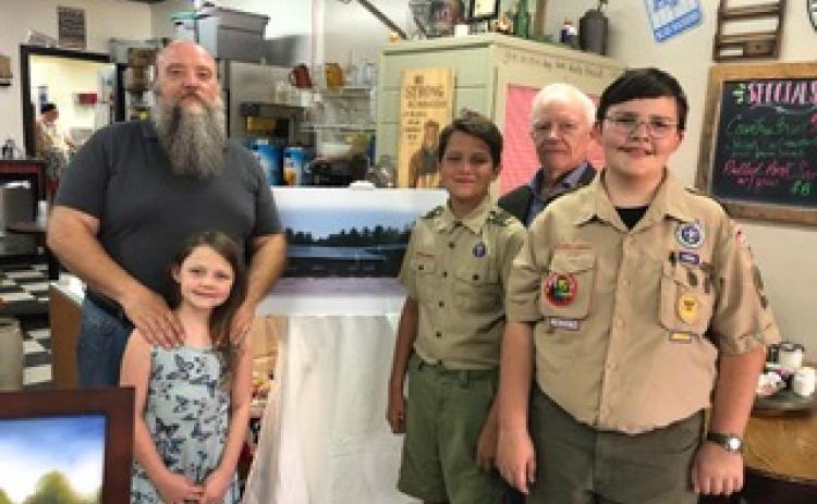  Wayne Knuckles/The Clayton Tribune. Ron Broz and Kaitlyn Craig, along with Tom Buckridge and local Scouts Alex Dizon and Liam Broz, show a rendering of a proposed new youth facility for Rabun County at a capital campaign kickoff last recently at Sunday Diner.
