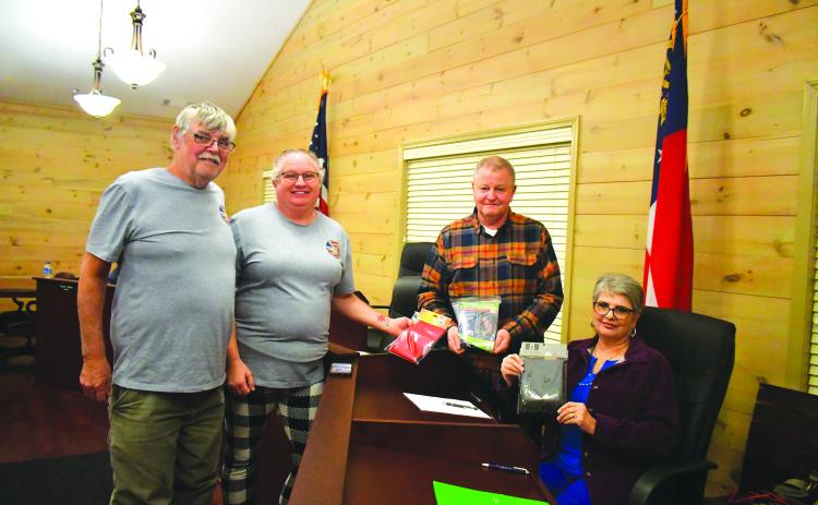 Megan Broome/The Clayton Tribune. Johnnie Robinson, president of the Board of Directors of Creating Ties that Bind, and Pam Wheeler, CEO of Creating Ties That Bind (left) present a United States flag, State of Georgia flag, and POW flag to Tiger Mayor Mike Carnes, center, and the Tiger Town Council at the Feb. 13 council meeting. Also pictured is Tiger Town Council member Karen Lovell. 