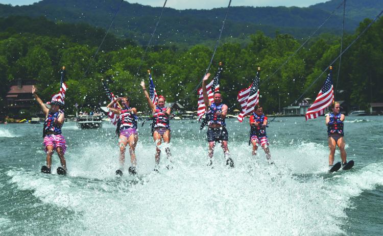 Enoch Autry/The Clayton Tribune. Members of the Ski Patriots wave toward people on balconies of houses on Lake Burton on July 1. In groups, the skiers went around the Rabun County lake for a total of 27 miles. This popular annual event has been putting smiles on individuals’ faces for the past 15 years. This time the youngest skier was 10 years old.