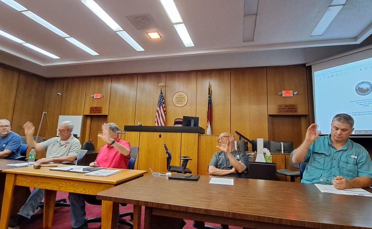Megan Horn/The Clayton Tribune. Rabun County Commissioners Tom Garrison, left, Kent Woerner, Greg James, Scott Crane and Will Nichols vote to approve the county's FY 2023 millage rate of 9.565 during a special called meeting Aug. 22. This is a rollback from the FY 2022 9.928 rate.
