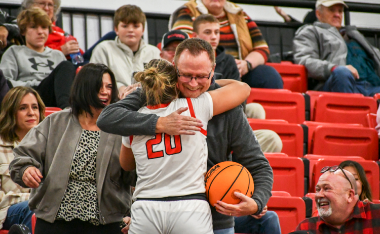 Wade Cheek/The Clayton Tribune. After giving him the game ball from her 1,000th career point, Rabun County Lady Cat senior Ellie Southwards hugs her father Gabe Southarsds in the stands on Jan. 13 at home in Tiger.