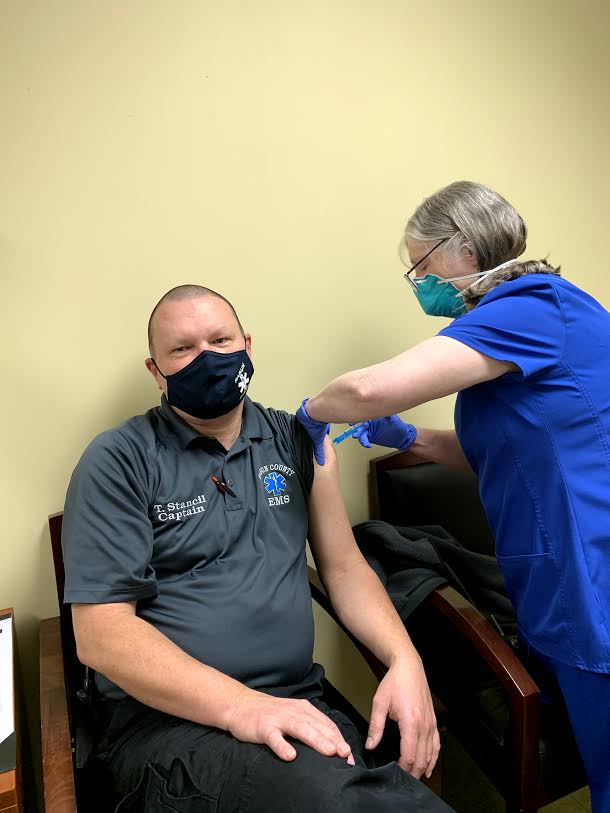 Photo courtesy Rabun County EMS. Captain Trampes Stancil, left, receives a COVID-19 vaccine administered by Josie Mosley at the Rabun County Health Department. EMS personnel are among the first to receive this vaccine. 
