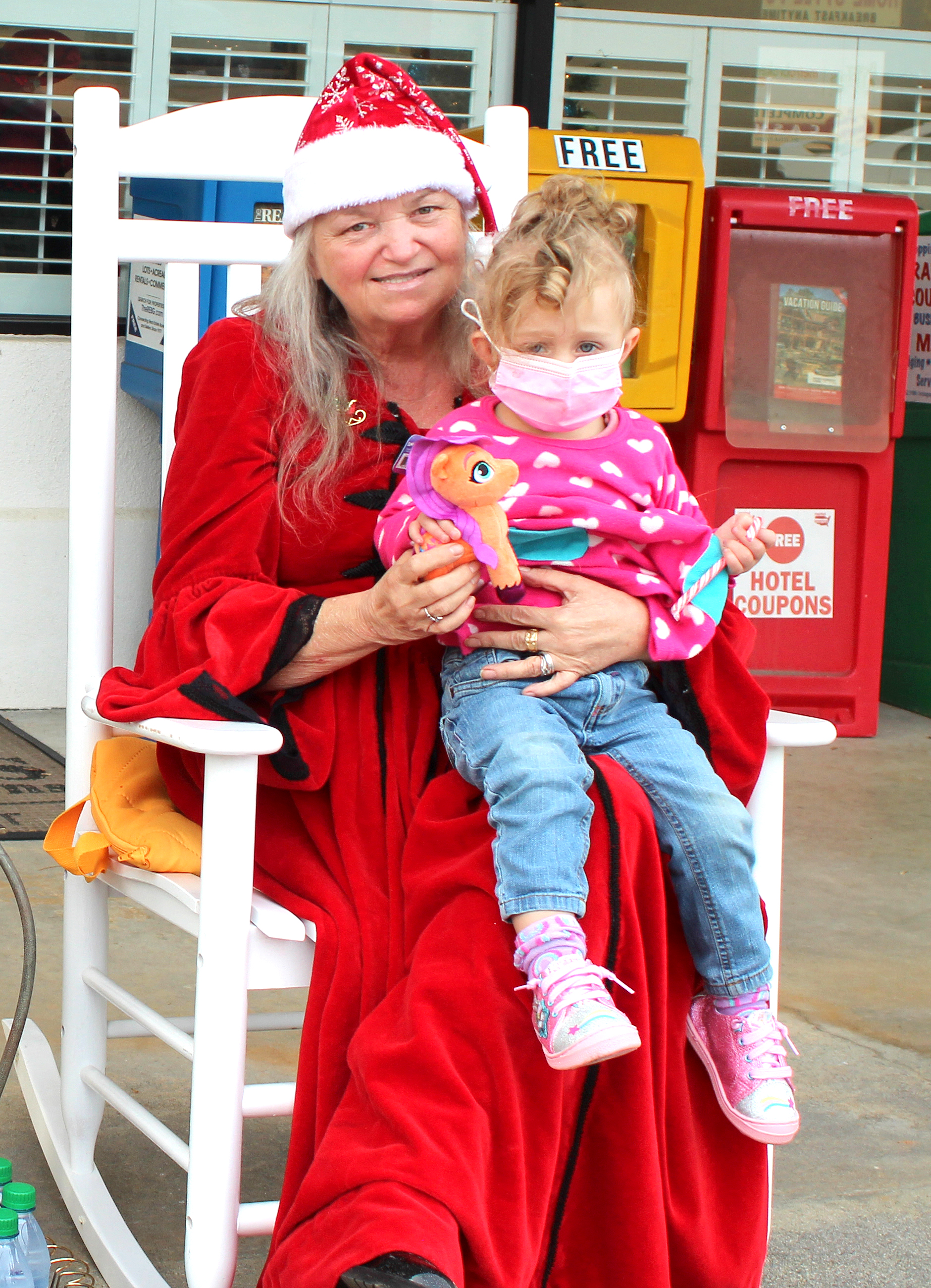 Megan Broome/The Clayton Tribune.  Lyndi Cox, 2, sits on Mrs. Claus’ lap at the Better Homes and Gardens Real Estate company in Clayton on Dec. 17. 