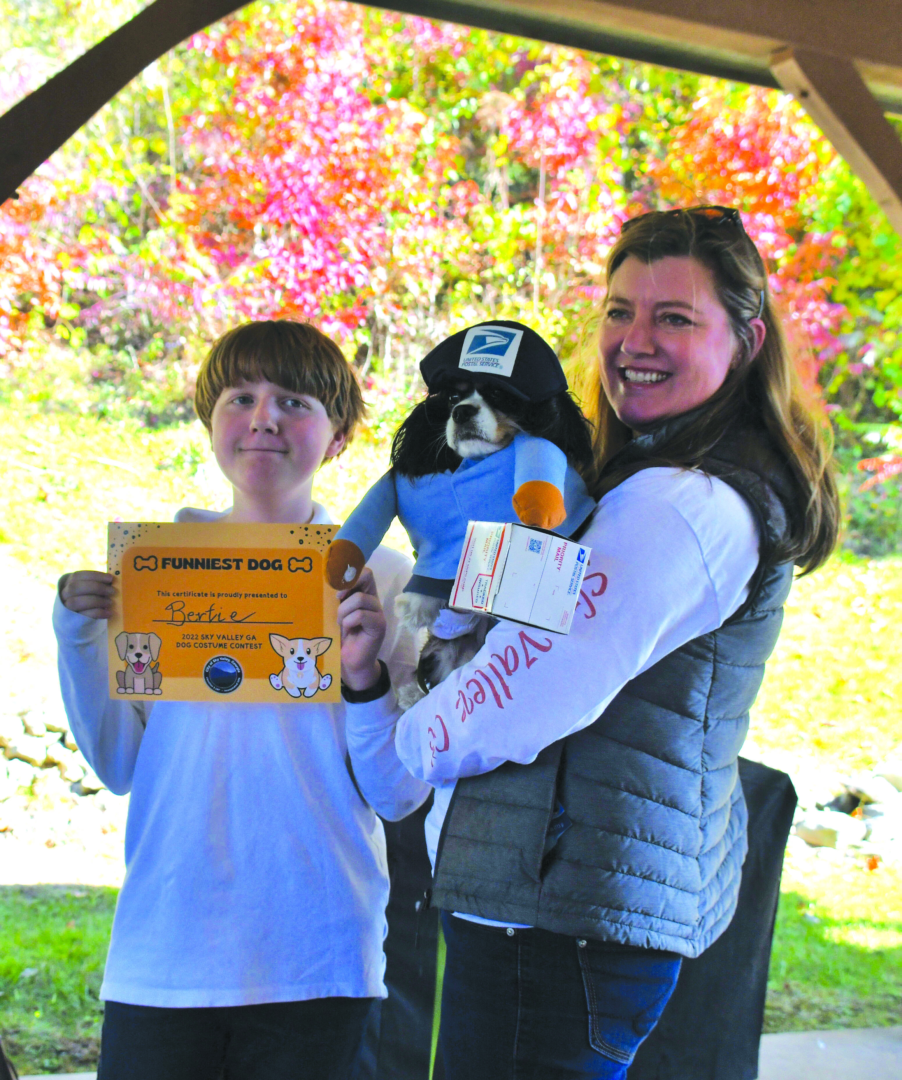 Megan Broome/The Clayton Tribune. Nash and Lillian Caudle hold their dog, “Bertie,” who is dressed as a USPS postal worker delivering a package at the Sky Valley Fall Fest event Saturday, Oct. 15. “Bertie” won Funniest Dog in the dog costume contest.