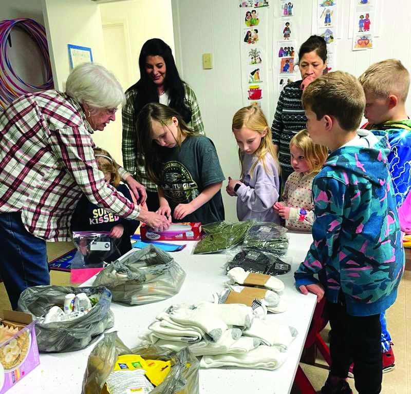 Photo courtesy Linda Page. Children at Wolffork Baptist Church in Rabun Gap work together to create “Blessing Bags” filled with clothes and food items that can be used to hand out to homeless people in the area. Several bags were given to First Impressions, a work-need ready clothes closet in Clayton, to be handed out to individuals in need. The bag donation was made on Monday morning.