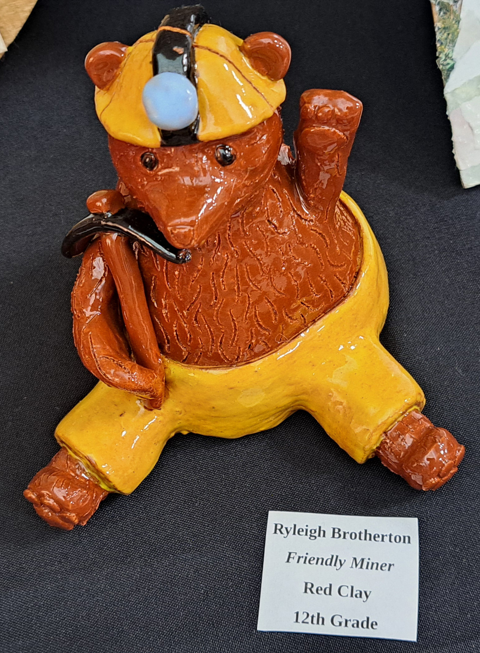 Megan Horn/The Clayton Tribune.  Left: RCHS senior Ryleigh Brotherton displays artwork in red clay titled “Friendly Miner."