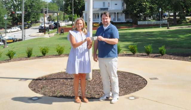 J. Todd Truelove/CNI News Service. The Toccoa Record Publisher Michael O’Hearn (right) presents Kim Caudell of Toccoa with the $100 she won for her photo in the 2025 summer Lake Living magazine cover contest.
