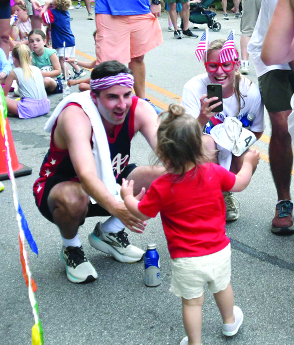 Enoch Autry/The Clayton Tribune.  Libby Foster, 21 months, walks toward her father Chris Foster as cousin Lee Ann Passarella videos the young lady after finishing the Rabun Ramble 5K. Libby did the course with her mother Laura Foster.