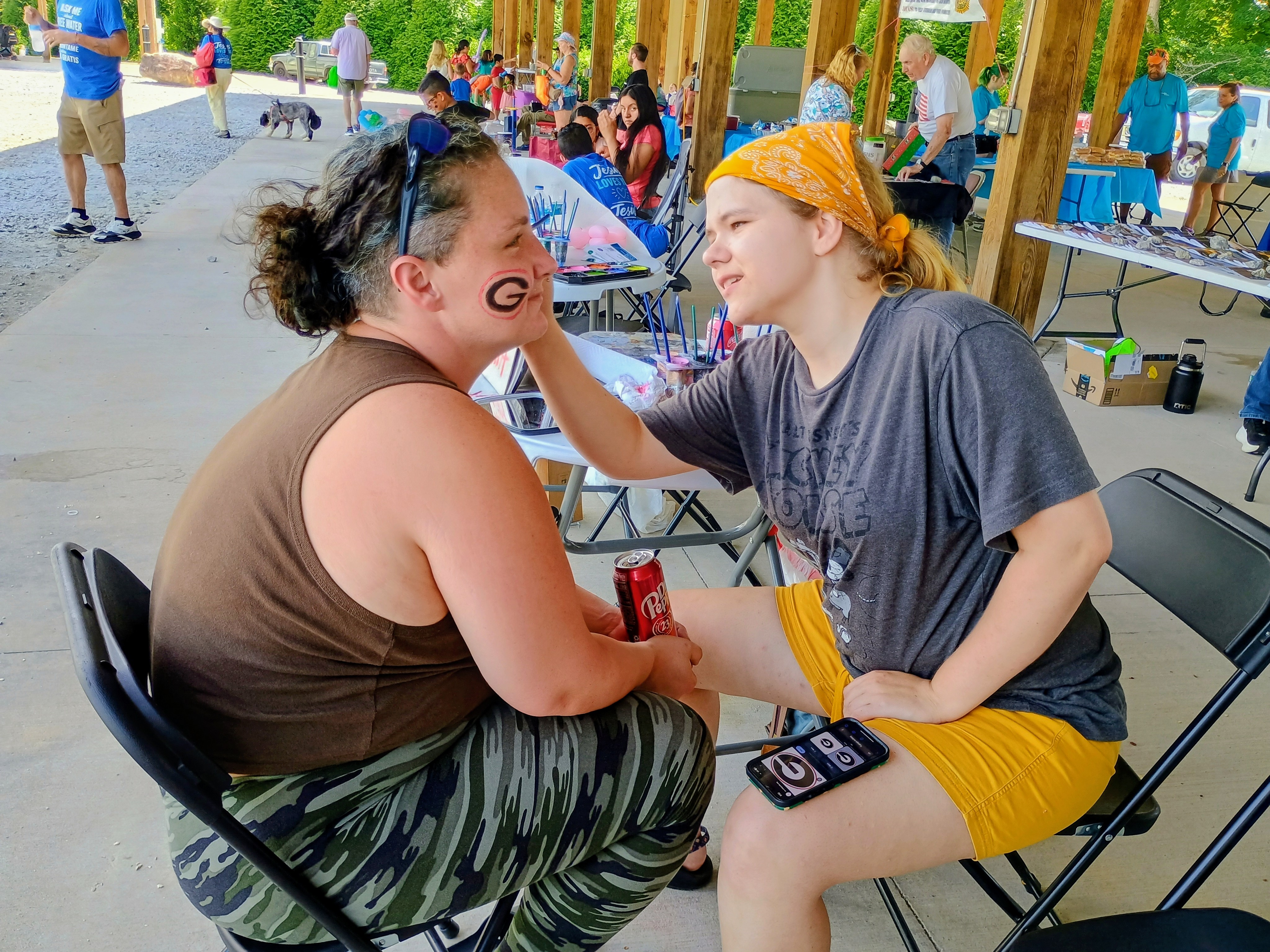 Megan Horn/The Clayton Tribune. Laura Ivey paints the face of Kayla Hughes during a Community Celebration held at the pavilions behind the Rabun County Civic Center last weekend. The free event was sponsored by the Rabun County Association of Southern Baptist Churches.  It featured bouncy games, balloon animals, car show and ice cream.