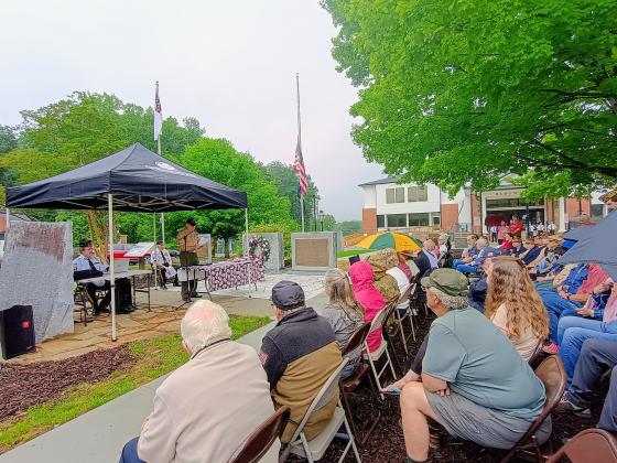 Megan Horn/The Clayton Tribune. Veteran Bruce Gant, left and center under the tent, speaks to a large crowd of community members during the May 25 Memorial Day ceremony held in front of the Rabun County Courthouse. Pictured on either side of Gant are Capt. Chris DiNofrio, U.S. Marine Corps, and Major (Ret.) Doug Wayne, U.S. Army. Gant was this year’s special guest speaker. He was a Navy Corpsman from September 1965 to September 1971. He is a Vietnam Combat veteran and two-time Purple Heart recipient. 