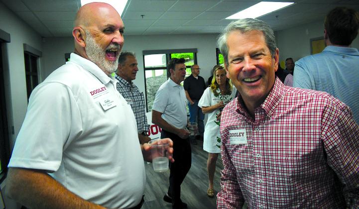 Enoch Autry/The Clayton Tribune. Clayton Mayor Roy Quilliams shares a laugh with Gov. Brian Kemp after the governor puts a Dooley for U.S. Senate sticker on Quilliams’ shirt at the May 29 Meet & Greet in Rabun County.