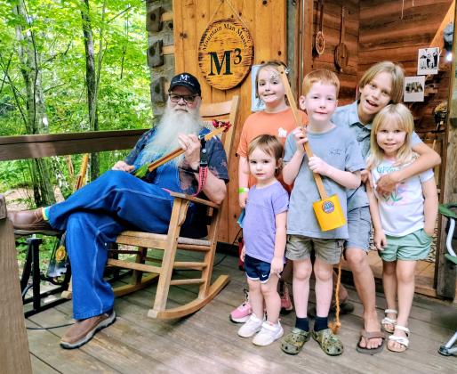 Megan Horn/The Clayton Tribune. Les Barnett with Mountain Man Music Custom Guitars showcases his unique panjos and canjos to kids at Foxfire Heritage Days. Barnett demonstrates his musical instruments to Chesney Godwin, 8; Tio O’Connell, 10; Astra O’Connell, 4; Emmy Kate, 2; and Henry Godwin, 5. 