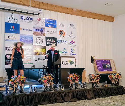 Megan Horn/The Clayton Tribune. Brenda Patterson, owner of White Birch Inn, White Birch Provisions and The Watchmaker’s Workspace, received the 2026 Entrepreneur of the Year award. Patterson thanked the community for their support. She stands on stage with Forward Rabun President Rick Story. 
