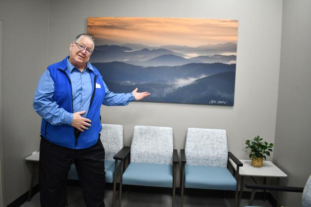 Megan Horn/The Clayton Tribune. Local photographer Peter McIntosh has 16 large pieces on display at MedLink Georgia Rabun Health Campus and hand-signed all of them. Here, he is pictured March 26 in front of his photograph capturing a view from Tennessee Rock Overlook at Black Rock Mountain State Park. McIntosh passed away on July 20. 