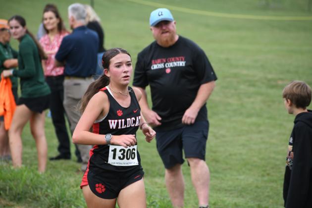Wesley Branch/The Clayton Tribune. Rabun County sophomore Kinley Jones runs during the Harrier Harvest meet at Tallulah Falls School on Sept. 24 as her father Brandon cheers her on. Jones was the top finisher overall for the girls with a time of 21:10.77.