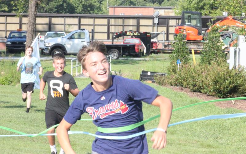 Paul Picciotti, front, crosses the finish line at Rabun County’s new pavilion, while Daniel Bills, middle, and Guy Gober trail during the Bicentennial Torch and Flag Run in Clayton on Saturday morning. (Glendon Poe/The Clayton Tribune)