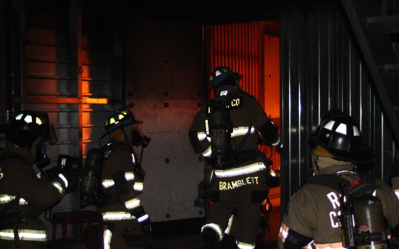 Firefighters for Rabun County Fire Services prepare to enter a room filled with smoke and flames in an exercise led by training instructor Ryan Bramblett, center, to provide annual emergency response training required for interior firefighters. The scenario took place at the training facility behind Station 4 in Lakemont.