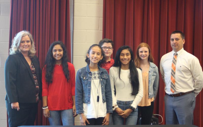Megan Broome/The Clayton Tribune. Superintendent April Childers, left, Vanessa Balderas, Itzia Vasquez, Justin Cody, Melanie Mendoza, Roseanna Carver and assistant superintendent Jonathan Gibson attend the REACH signing ceremony in the Rabun County Band Room last Friday.