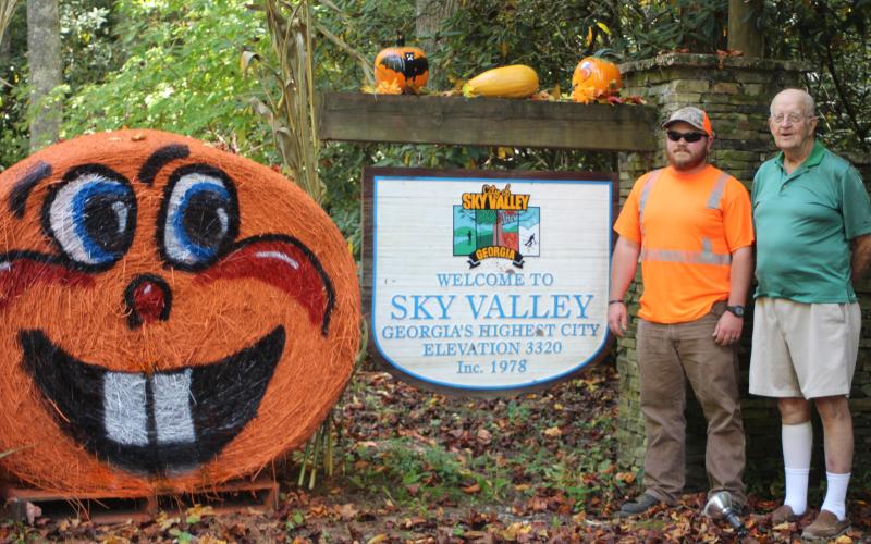 Cody English, left, Sky Valley public works employee, and Sky Valley Mayor Robert MacNair reveal Sky Valley's Fall decorations at the entrance to the city. The city has 13 hay bales that were painted by English and they stay out through the month of October.