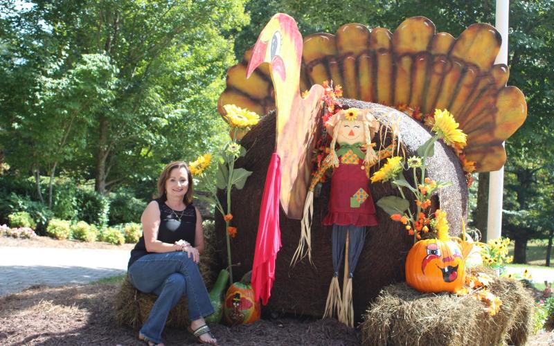 Ella Fast, city manager of Sky Valley, sits on top of a bale of hay beside a giant Turkey created out of hay for Sky Valley's Fall decorations throughout the city.