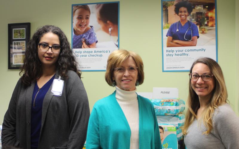 Megan Broome/The Clayton Tribune. Amerigroup Community Care sponsored “Diaper Day” on Tuesday, Jan. 28 at the Rabun County Health Department. From left, Sarah Pedraza, representative from Amerigroup, Sue Darnell, office manager for the Rabun County Health Department, and Lacy Carter pose in front of a table of donated diapers at the “Diaper Day” event.