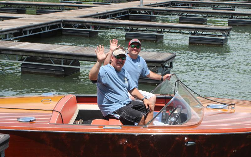 Megan Broome/The Clayton Tribune.Fred Beck, left, and Hunter Hargrave showcase Beck’s 1959 Chris Craft wooden boat named “Tallulah” at LaPrade’s Marina following Lake Burton’s first-ever Wooden Boat Parade. The whole boat is completely original and has been on Lake Burton its entire life.
