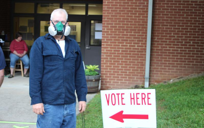 Megan Broome/The Clayton Tribune. Charles Wilkins wears a respirator mask as he participates in early voting at the Rabun County Board of Elections Office Monday. Voters are required to stand six feet apart as one person at a time goes into the building to cast their ballot. These areas are marked with tape along the sidewalk. This is part of COVID-19 precautions mandated by the state of Georgia.