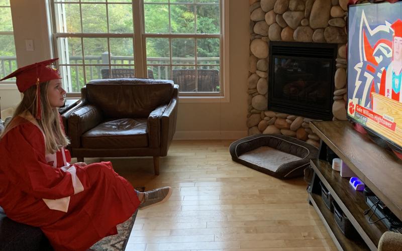 Photo courtesy Grace Nolan. Grace Nolan wears her cap and gown while watching the virtual commencement addresses from fellow classmates.