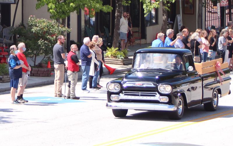 Megan Broome/The Clayton Tribune. The body of Lewis Reeves, Jr. was taken past Reeves Hardware a final time Saturday in a restored Reeves pickup truck as employees and members of the community pay their respects.