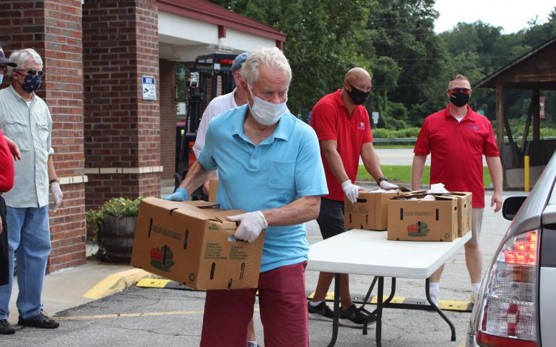Megan Broome/The Clayton Tribune. Rotarians Ray Pagano, Matt Mitchum, James Brim and Tony Penrose help load food into vehicles. 