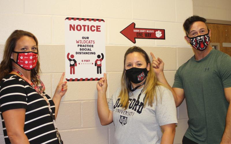 Megan Broome/The Clayton Tribune. Lori Keller, left, Alicia Kilby and John Kilby produced a video parody of Aerosmith’s “Walk This Way” as a fun way to show Rabun County Middle School students what to expect with COVID-19 precautions when school starts back. The video quickly went viral after being posted on social media.