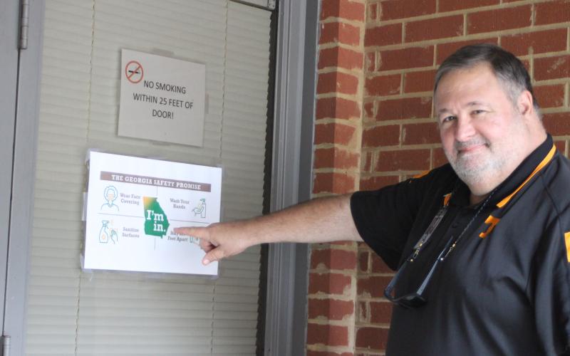 Megan Broome/The Clayton Tribune. Chuck Leming, technician for Dominion Voting Systems, points to a sign posted by the Rabun County Board of Commissioners Office that encourages voters to wear masks and maintain social distancing while at the polls.