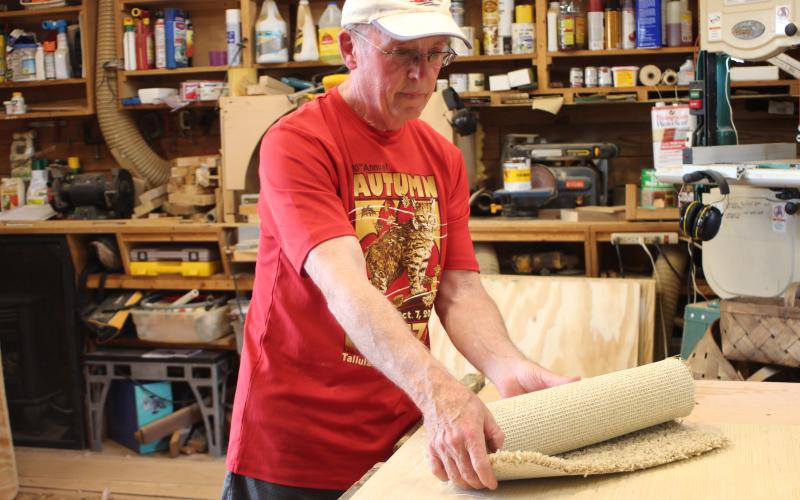 Megan Broome/The Clayton Tribune. Ervin Leonard makes the dog houses for Habitat for Hounds and demonstrates how the doghouse door, which is made out of carpet, can be rolled up and velcroed during the hot summer months to allow for a breeze.