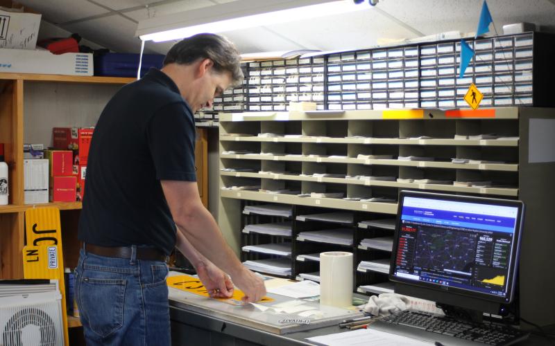 Megan Broome/The Clayton Tribune. Keith Yunger, sign technician for the Rabun County mapping department, makes signs to post throughout the county.
