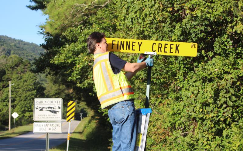 Megan Broome/The Clayton Tribune. Keith Yunger, sign technician for the Rabun County mapping department, replaces one of the road name signs located on Warwoman Rd. that was stolen on Labor Day weekend. A total of 80 signs were reported stolen, along with one stop sign and seven stop signs damaged. Yunger installs all of the road signs in the county.