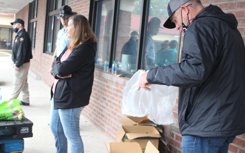 Megan Broome/The Clayton Tribune. Sgt. Casey Coffee of Georgia State Patrol, left, Investigator Channon Pritchard of the Rabun County Sheriff’s Office and Sheriff Chad Nichols distribute food to families last Saturday.